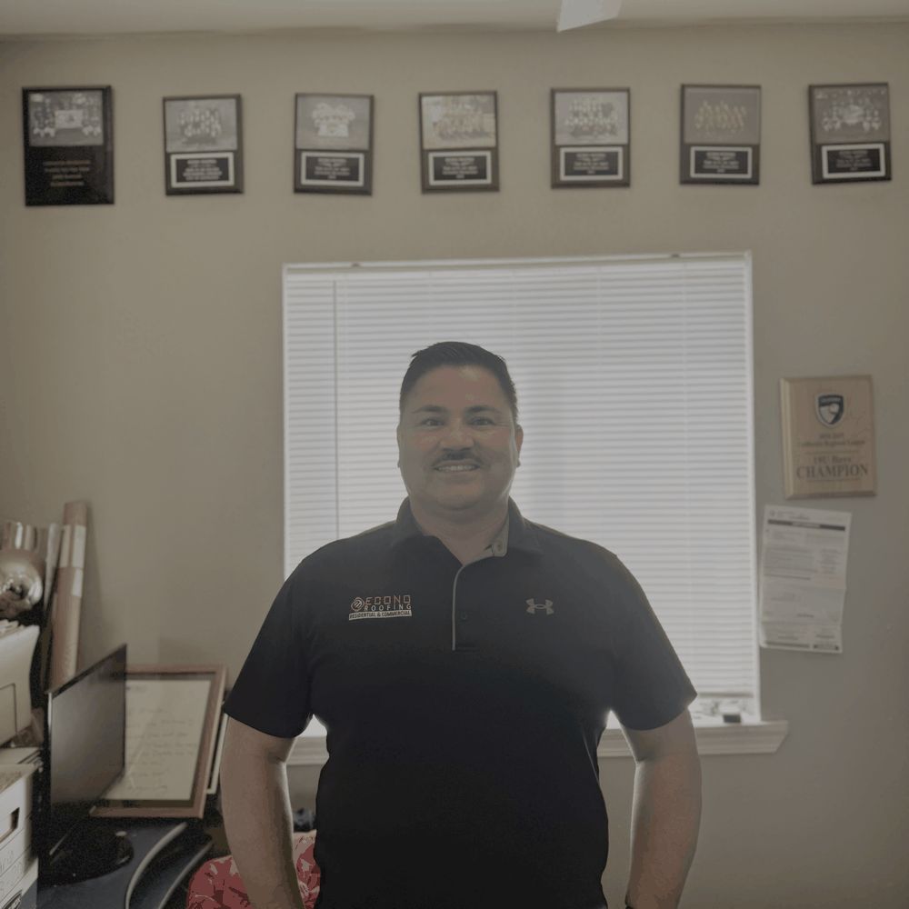Mario Espindola, founder of Econo Roofing, in front of the company's certification wall