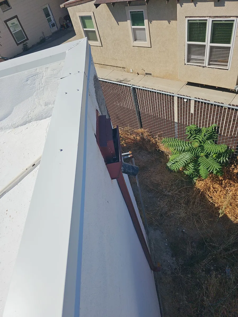 Freshly coated white flat-roof edge with new metal parapet cap flashing at Beto's Bakery, Modesto