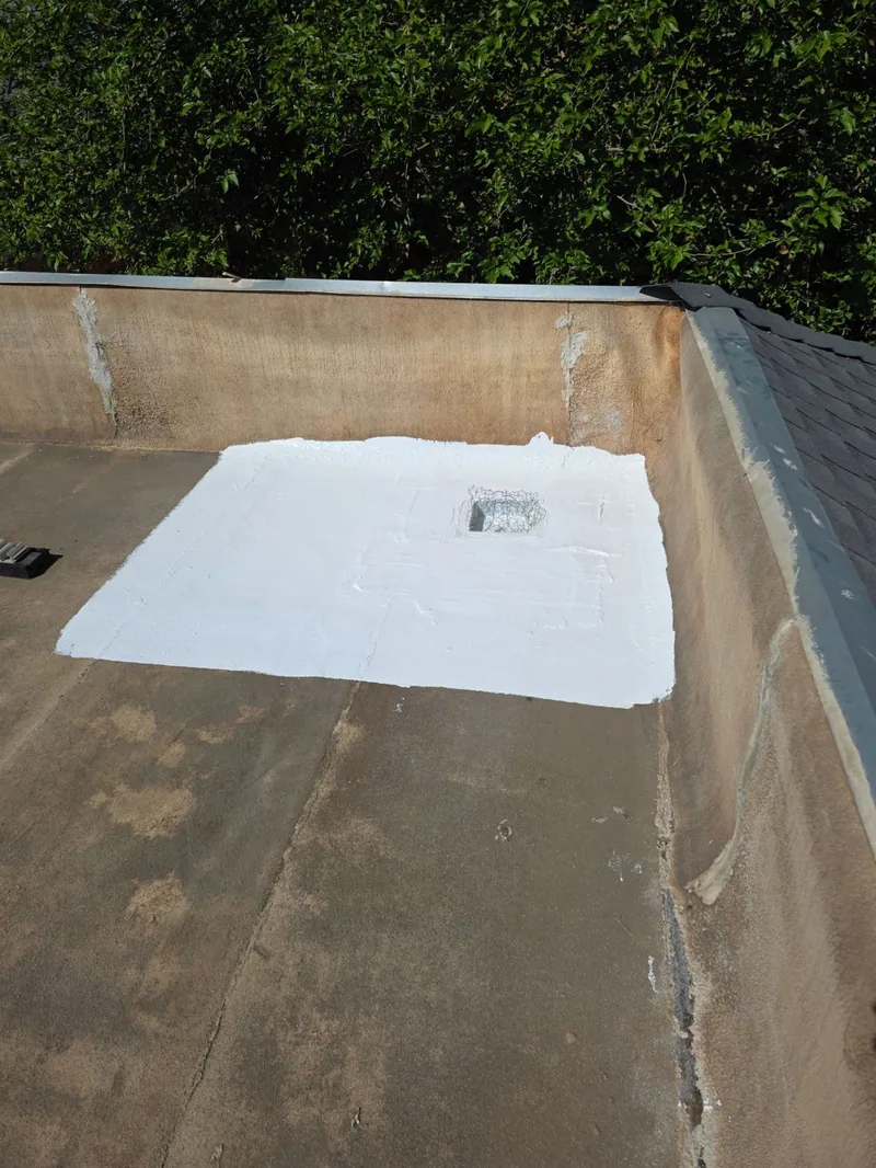 New white waterproofing patch around the rebuilt roof drain on the Modesto flat roof