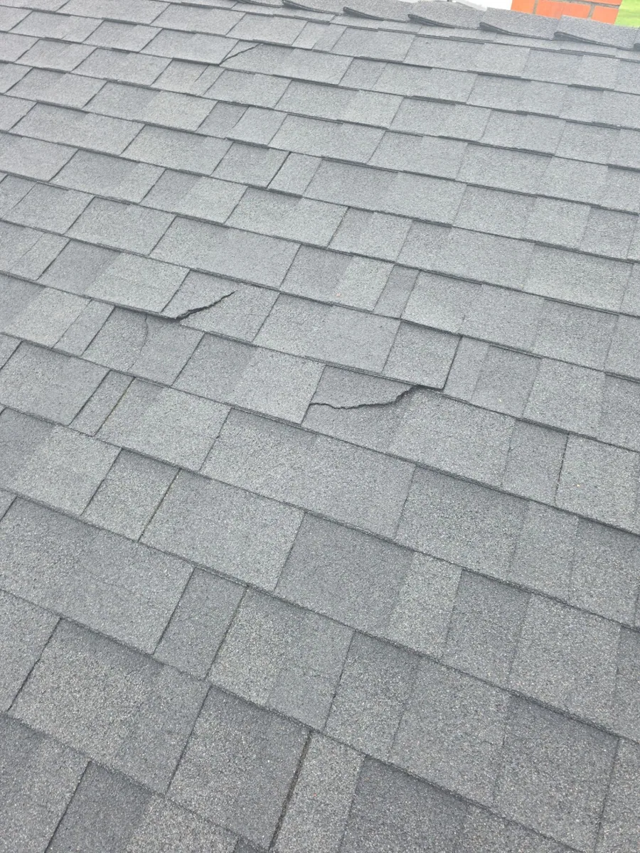 Cracked and worn composition shingles with exposed nail pops on the Turlock home before replacement