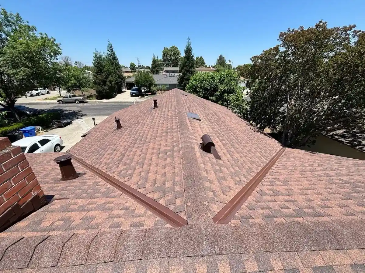 Completed red-blend architectural shingle re-roof with new ridge caps and vents in Turlock, CA