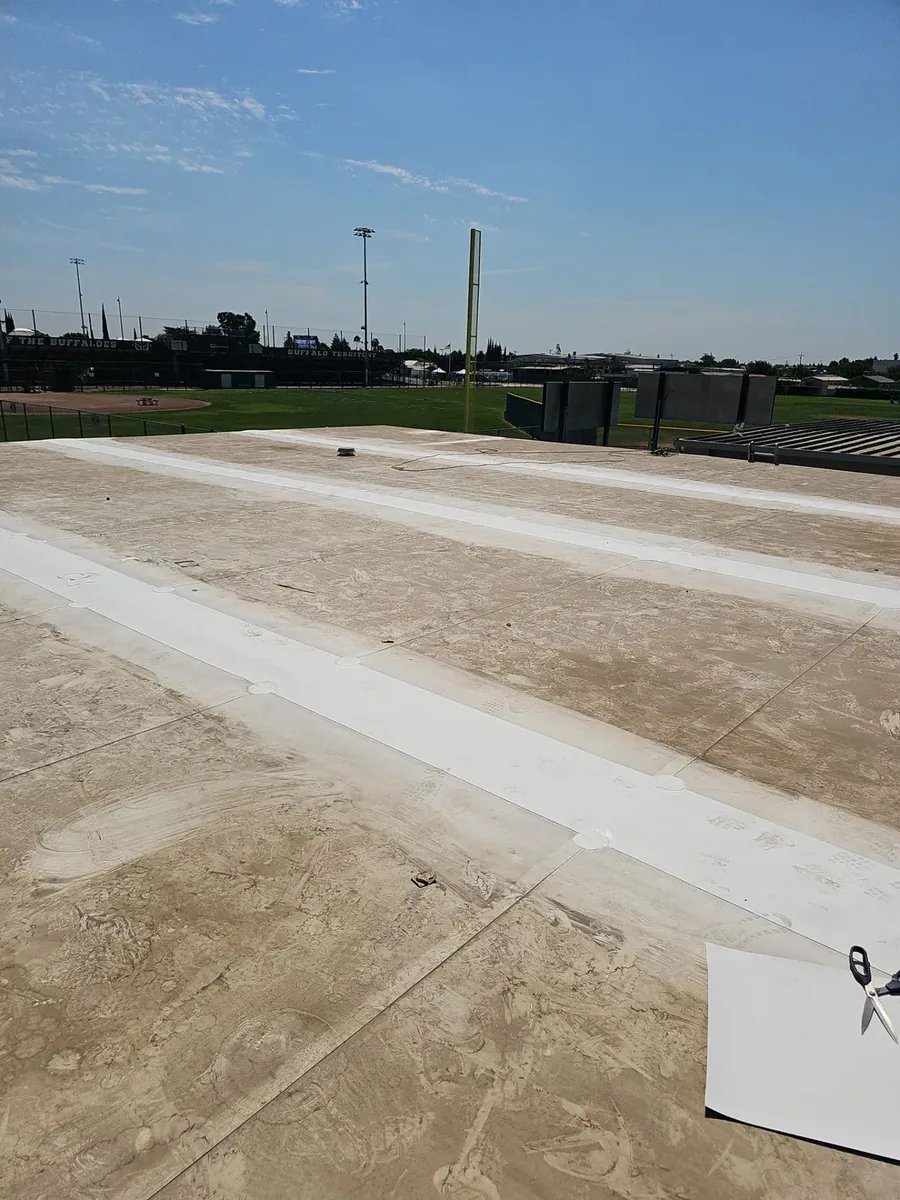 New white TPO seams across the Manteca High School roof deck, overlooking the baseball field and Buffalo Territory banners