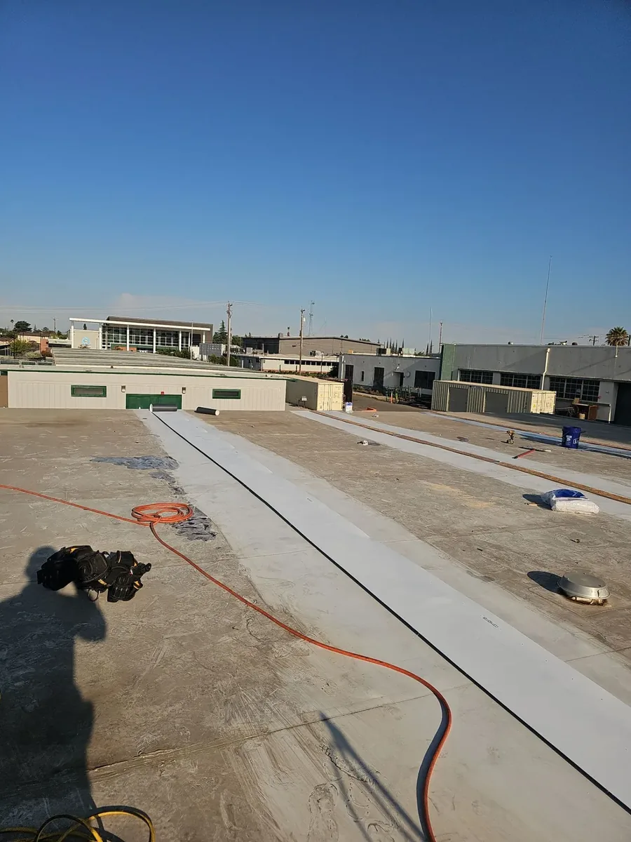 Long white TPO membrane strips laid across the flat roof deck during the Manteca High School re-roof