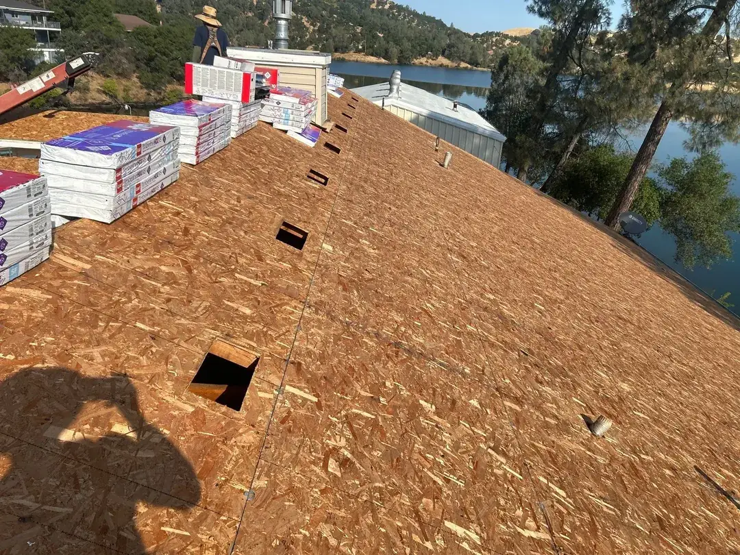 Roof deck re-sheeted with OSB and shingle bundles staged along the ridge during the Jamestown roof replacement