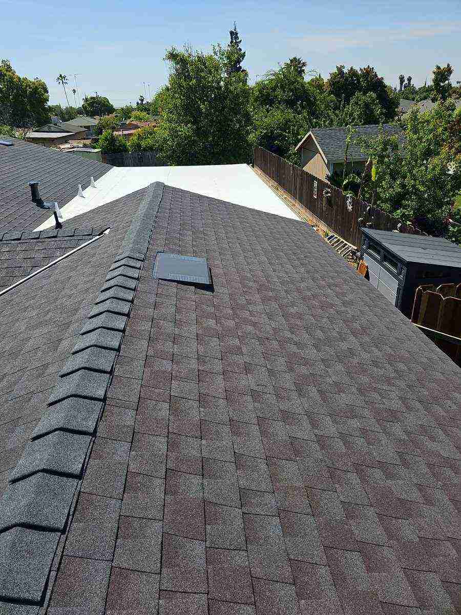 Crew working on exposed roof deck with GAF shingle bundles, complex multi-hip roof geometry