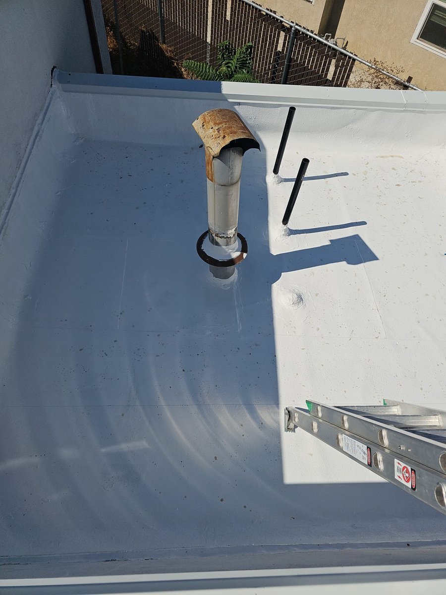 Pristine white elastomeric coating around pipe penetrations at Beto's Bakery after coating