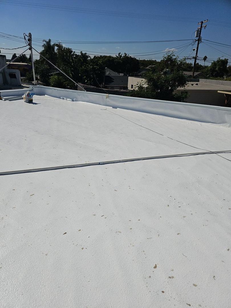 Wide roof surface showing uniform white coating across full commercial roof