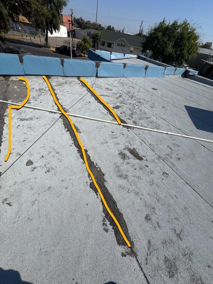 Cracked seams with yellow damage markup on commercial flat roof