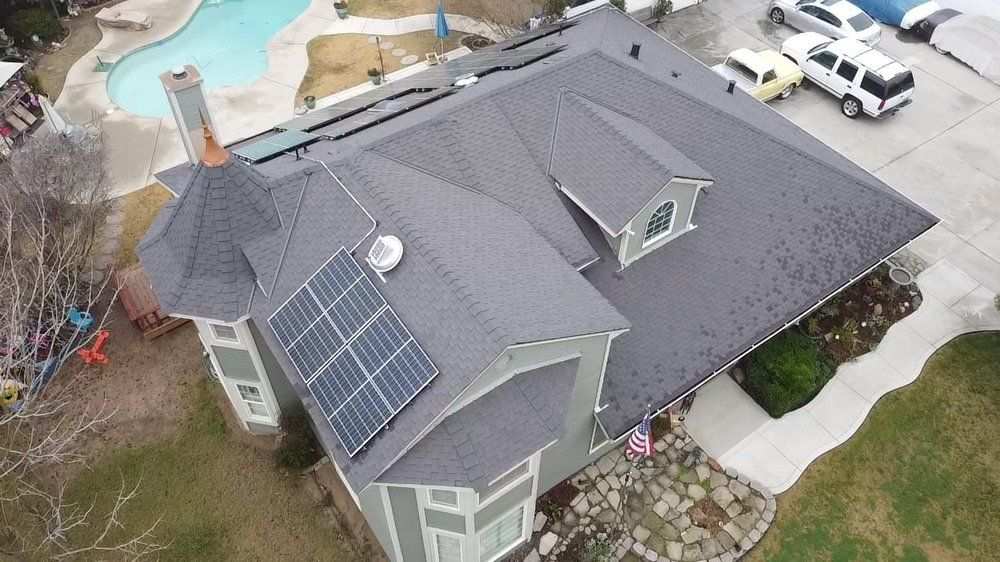 Aerial view of an Econo Roofing home with dark architectural shingles and rooftop solar panels